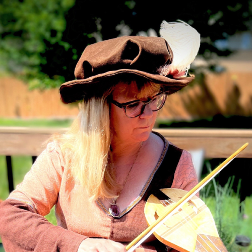 The Arts and Sciences Minister holding a string instrument and wearing a brown hat with a white feather.